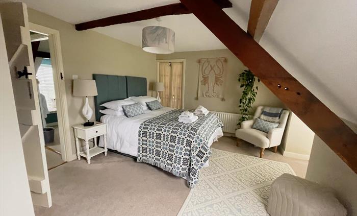 Kingsize bedroom at Seadog and Stone Ysgubor Degwm with white linens and a welsh tapestry throw in blues. Lobster wall art.